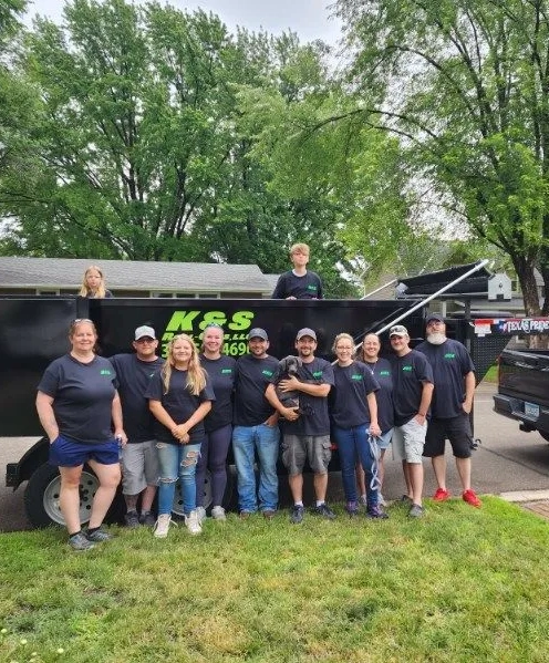 group of people gathered in and around a k&s roll-off dumpster